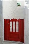 Close-up view of red gate and green chair at house entrance with stairs, Greece