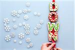 Overhead View of Decorated Christmas Cookies spelling DOWN on Blue Background with Snowflakes