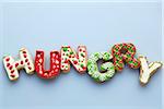 Overhead View of Christmas Sugar Cookies spelling HUNGRY on Blue Background