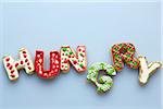 Overhead View of Christmas Sugar Cookies spelling HUNGRY with Bite out of one on Blue Background