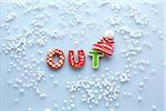 Overhead View of Sugar Cookies spelling OUT with Touque and Snow on Blue Background