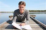 Young man reading on jetty