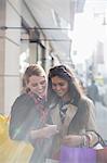 Women looking at cell phone together on city street