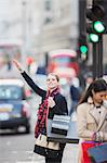 Woman hailing taxi on city street