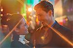 Couple hugging on city street at night