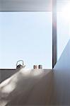 Low angle view of teapot and cups on windowsill