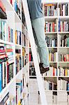 Man standing on ladder to reach books in library