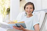 Smiling woman reading book in lawn chair