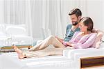 Couple using laptop on sofa in modern living room