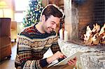 Man using digital tablet in front of fireplace