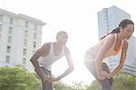 Couple stretching before exercising on city street