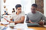 Businessmen looking at digital tablet in meeting