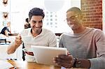 Businessmen using digital tablet in cafe