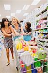 Women pushing full shopping cart in grocery store