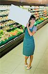 Clerk holding blank card in grocery store produce section