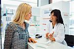 Woman discussing product with pharmacist in drugstore