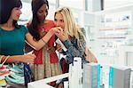 Women smelling perfume in drugstore