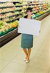 Clerk holding blank card in produce section of grocery store