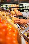 Close up of man selecting produce in grocery store