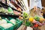 Man carrying full shopping basket in grocery store