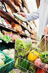 Close up of man holding full shopping basket in grocery store