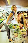 Woman playing on shopping cart in grocery store