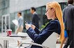 Businesswoman using cell phone at table outside