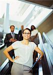 Businesswoman riding escalator in office building