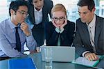 Business people gathered around laptop at table in office building