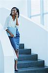 Businesswoman walking on cell phone on stairs of office building