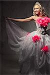 Lovely woman wearing white dress decorated with pink feather boa posing indoors