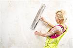 Female with putty knife working indoors