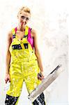 Tired female construction worker with putty knife working indoors