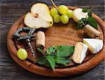 Wine frame background. Cheese and fruit on a wooden serving board.