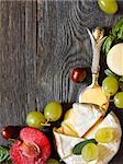 Assortment of delicious cheeses and fruit on a wooden background with copy space for text.