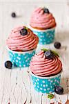 Delicious blueberry cupcakes on an old wooden board.