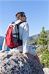 young healthy man resting at the rock after hiking near lake tahoe, california, travel and health concept