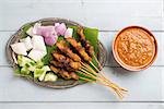 Fresh chicken satay on wooden dining table, one of famous Malaysian local dishes.
