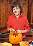 Closeup of boy carving a pumpkin Halloween jack-o-lantern - removing the seeds