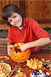 Boy preparing for Halloween - carving a pumpkin jack-o-lantern outdoors