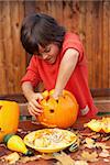 Boy busy carving a pumpkin jack-o-lantern for Halloween - removing the seeds
