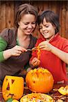 Boy and his mother having fun carving a jack-o-lantern for Halloween