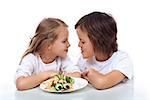 Kids sipping on the same string of pasta - sharing a plate of healthy food, isolated