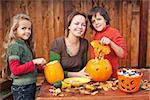 Kids carving jack-o-lanterns for Halloween - with a little help from their mother