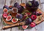 Ripe purple figs, plums, thyme and homey on olive board. Selective focus.