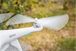 blurred spinning propellers of a small helicopter drone (quadcopter) flying over backyard with dry leaves