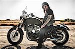 Portrait of mature man on motorcycle on arid plain, Cagliari, Sardinia, Italy