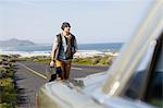 Young man behind parked car with guitar case, Cape Town, Western Cape, South Africa