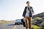 Young man walking along road with guitar case, Cape Town, Western Cape, South Africa