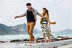 Young couple walking along cement block on beach, Cape Town, Western Cape, South Africa